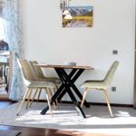 Esstisch mit vier Stühlen vor einem Fenster mit Blick auf Balkon.