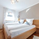 Schlafzimmer mit Holzbett, Fenster und Nachttisch.