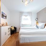 Schlafzimmer mit Bett, Schrank und Fenster mit Vorhängen.