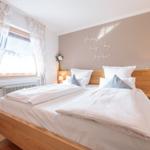 Ein Schlafzimmer mit Holzbett, Fenster und Wanddekoration.