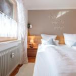 Schlafzimmer mit Doppelbett, Holz-Kopfteil und Wanddekoration.