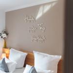 Schlafzimmer mit Bett, Wanddekoration und Blumenvase.