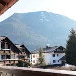 Blick auf Berge mit Wald, traditionelle Häuser und Balkon im Vordergrund.