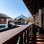 Balkon mit Holzgeländer und Blick auf Berg und Häuser