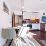 Essbereich mit Tisch, Stühlen und Küchenbereich im Hintergrund.