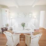 Wohnzimmer mit weißem Sofa, zwei Stühlen und Kamin. Holzboden und Wandbilder.