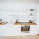 Küche mit weißen Schränken, Holzoberflächen und integriertem Ofen.