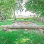 Hinterhof mit Sandkasten, Spielplatz und Grünfläche.