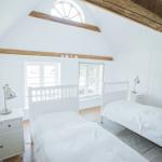 Zwei Betten mit weißen Laken, zwei Nachttische und Fenster mit Blick nach draußen.