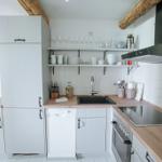 Küche mit Holzoberflächen, weißen Schränken und Edelstahlgeräten.