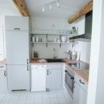 Küche mit hellen Schränken, Holzoberflächen und integriertem Spülmaschinenplatz.