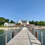 Holzbrücke führt zum Strandhotel mit Strand und Badegästen.
