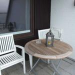 Terrasse mit runden Tisch und zwei weißen Stühlen. Hintergrund: Fenster und weißer Ziegelstein.