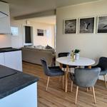 Essbereich mit runden Tisch und Stühlen, Küche und Wohnbereich im Hintergrund.