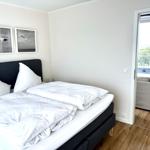 Schlafzimmer mit Doppelbett, Wandbildern und Zugang zum Balkon.