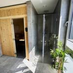 Dusche mit Glaswand und Sauna mit Holztür