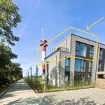 Moderne Villa mit Balkon und rotem Turm im Hintergrund.