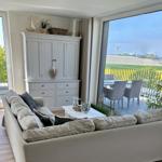 Wohnzimmer mit Sofa, Schrank und Balkonblick auf Hafen