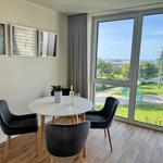 Rundtisch mit drei Stühlen und Blick auf Grünflächen und Meer.