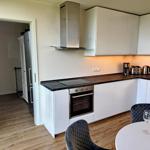 Moderne Küche mit weißen Schränken, Edelstahlgeräten und Esstisch.