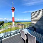 Terrasse mit Tisch und Stühlen, Blick auf Leuchtturm und Meer.