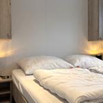 Schlafzimmer mit Bett, Nachttisch und Wandregalen.