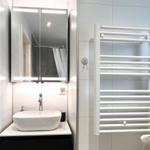 Badezimmer mit Waschbecken, Spiegel und Handtuchheizung.