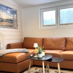 Ein Wohnzimmer mit braunem Sofa, Tisch und Fenstern.