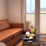 Ein braunes Ledersofa steht vor einem Fenster mit Jalousien. Davor steht ein runder Tisch mit Lampe und Pflanze.