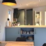 Küche mit blauen Schränken und Holzoberfläche. Im Hintergrund sind Schlafzimmer sichtbar.