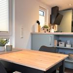 Essbereich mit Holztisch und Küchenzeile im Hintergrund.