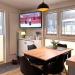 Essbereich mit Tisch, Stühlen und Fernseher an der Wand.