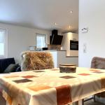 Esstisch mit Fellbezogenen Stühlen und Küchenbereich im Hintergrund.