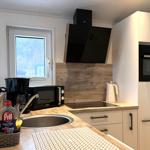 Küche mit Spüle, Dunstabzug, Kühlschrank und Fenster.