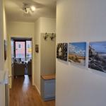 Flur mit Wandbildern und Blick in Wohnbereich mit Sofa und Balkon.