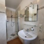 Badezimmer mit Dusche, Waschbecken und Spiegel