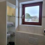 Badezimmer mit Fenster, Regal und Heizung