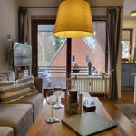 Wohnzimmer mit Sofa, Couchtisch und Balkonansicht. Küche im Hintergrund.