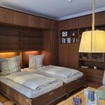 Zimmer mit zwei Betten, Holzmöbel und einer Lampe.