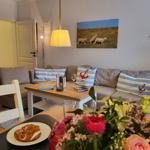Wohnzimmer mit Sofa, Tisch und Blumen. Wandbild zeigt Schafe.