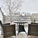 Terrasse mit Tisch und Stühlen, Blick auf schneebedeckte Dächer und Bäume.