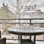 Terrasse mit Tisch und Stühlen, Blick auf schneebedeckte Dächer und Bäume.