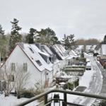 Schneebedeckte Häuserzeile mit Straße und Bäumen im Winter