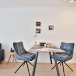 Essbereich mit Tisch und zwei Stühlen, Sofa und Wandbilder