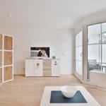 Wohnzimmer mit Fernseher, Schiebetür und Sicht auf Balkon