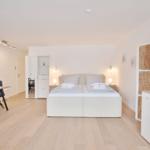 Schlafzimmer mit Bett, Schreibtisch und Fernseher.