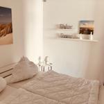 Schlafzimmer mit Bett, Wandbild und Regal mit Dekoration.
