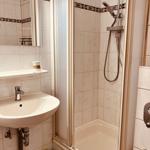 Badezimmer mit Dusche, Waschbecken und Spiegel.