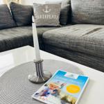 Grauer Sofa mit Kissen und Kerze auf Tisch