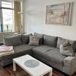 Wohnzimmer mit grauem Ecksofa, weißem Tisch und Wandbild